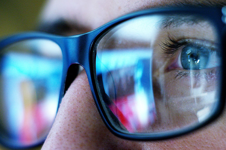 Reflections of a computer screen in persons glasses