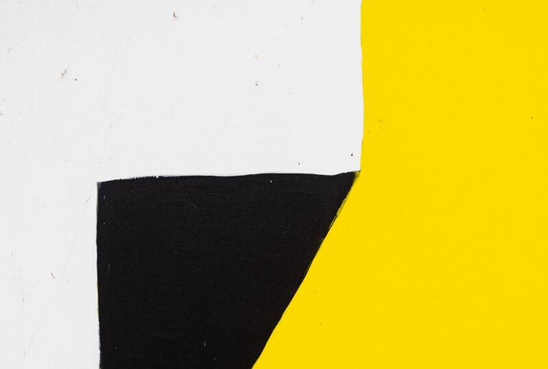 Yellow, black and grey abstract shapes painted on a wall.