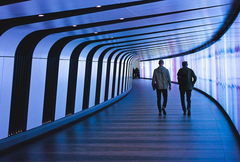 Two people walking down a futuristic looking corridor